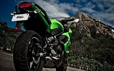 Green Kawasaki Motorcycle resting at the bottom of a mountain